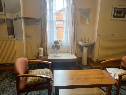 a bathroom with a table and a sink and a window at Hylands Hotel Family Room with Free Parking in Nottingham