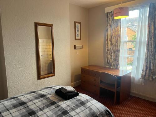 a bedroom with a bed and a dresser and a mirror at Near Hylands hotel family room in Nottingham
