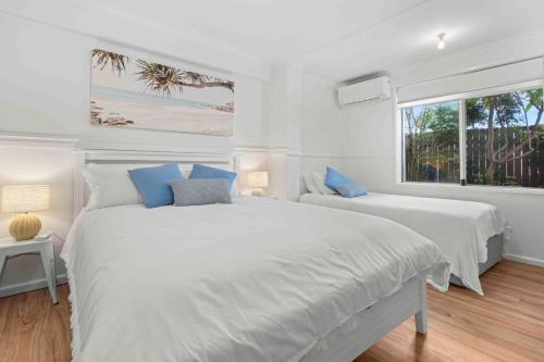 ein weißes Schlafzimmer mit zwei Betten und einem Fenster in der Unterkunft 4 Bedroom Pet Friendly Home - 150m to Culburra Beach in Culburra Beach