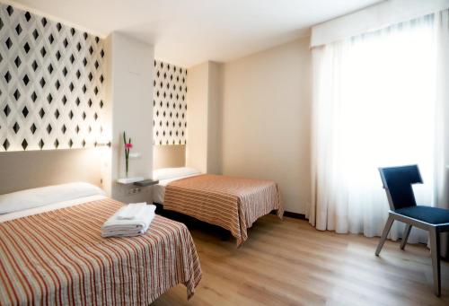 a hotel room with two beds and a chair at Hotel Plaza Santa Lucía in Seville