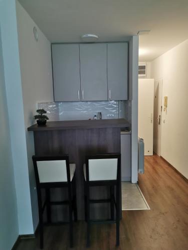 Eine Küche mit einer Theke mit zwei Stühlen und einem Spülbecken in der Unterkunft Andrej 62 in Beograd