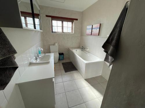a white bathroom with a tub and a sink at Klipwerf in Struisbaai