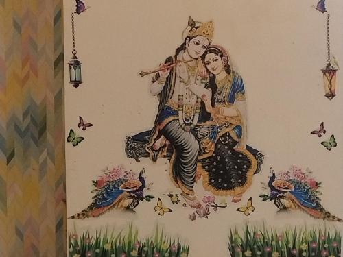a painting of two women sitting on a wall at Rudra Prabha Guest House front of Ram Mandir VIP gate number 11 Ayodhya dham railway station 200 metre in Ayodhya
