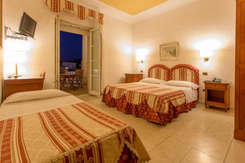 um quarto de hotel com duas camas e uma varanda em Mariano IV Palace Hotel em Oristano