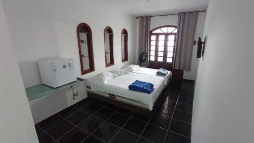 a bedroom with a white bed and a window at Pousada casa nostra in Piúma