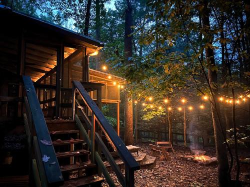 a cabin with lights in the woods at night at Hot Tub Fire Pit Grill Sleeping Porch & More in Mount Trimble