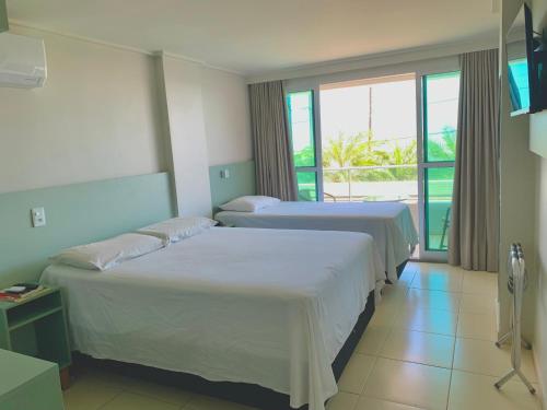 due letti in una stanza d'albergo con finestra di Flat JP Beira mar a João Pessoa