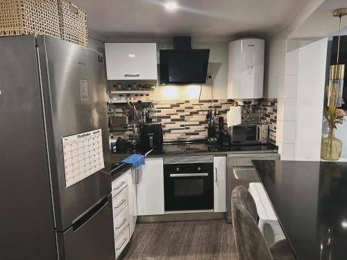 a kitchen with a stainless steel refrigerator and white cabinets at Cacém Maison in Cacém