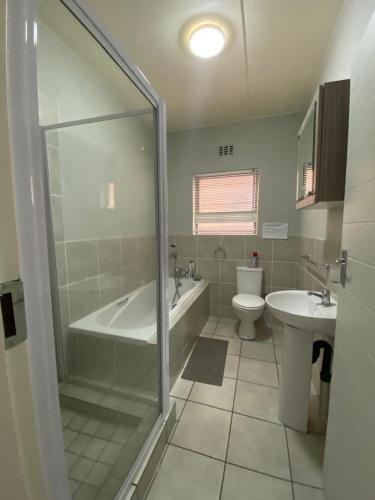 a bathroom with a tub and a toilet and a sink at Yanaz Place in Germiston