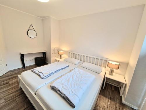 ein Schlafzimmer mit einem großen weißen Bett mit zwei Lampen in der Unterkunft Ferienwohnung Seestern in Fehmarn
