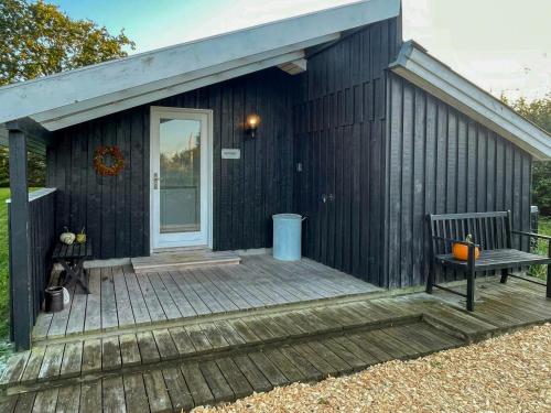a black house with a bench on a wooden deck at Holiday Home Near Fjerritslev With Fenced Garden in Fjerritslev