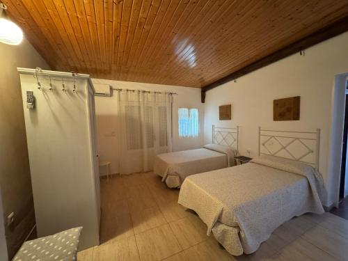 a bedroom with two beds and a wooden ceiling at Casa Rural Cornalvo in Mirandilla