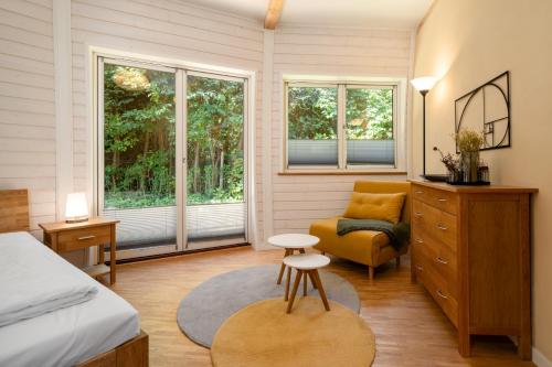 a bedroom with a bed and a chair and windows at Kugelhaus Solveig - Zeitloses Holzhaus in Kugelform für stille Momente in der Natur in Wustrow