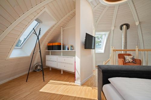 a room with a bed and a tv in a attic at Kugelhaus Kugellager - Besonderer Rückzugsort in runder Bauweise - reduziert, ruhig und naturnah am Tollensesee in Wustrow