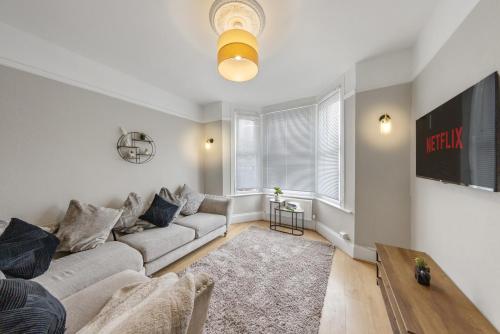 a living room with a couch and a tv at modern 4 bdr house rock ave in Gillingham