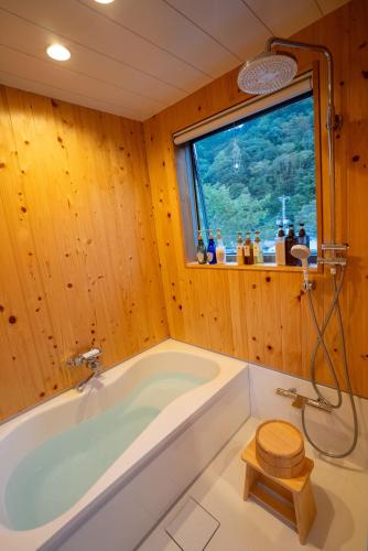 a bathroom with a tub and a window at Silver Daisy Stay Nikko in Nikko