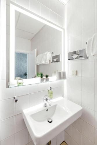 a white bathroom with a sink and a mirror at Pallas Hotels in Darmstadt