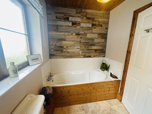 a bath tub in a bathroom with a wooden wall at Bay View in Pendine