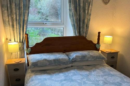 a bedroom with a bed with a window and two night stands at Talcomb Cottage in Thornthwaite Keswick in Keswick