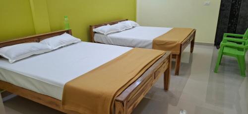two beds in a room with a green wall at A J Home Stay in Tiruvannāmalai