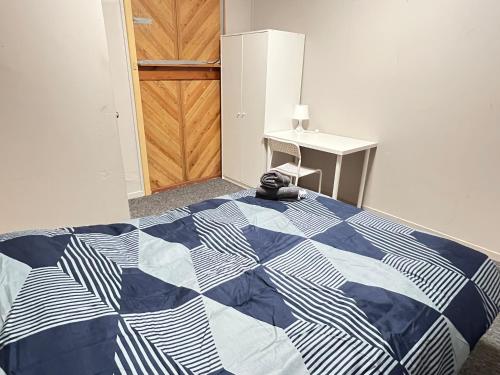 a bedroom with a blue and white quilt on a bed at Cozy Queen Room Next to Station and Shops - PH6 in Pendle Hills