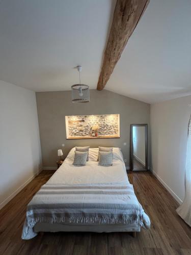 a bedroom with a large bed with a painting on the wall at Charmante ferme familiale in Guitalens