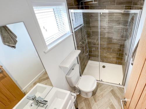 Un baño con inodoro, lavabo y espejo. en Hoburne, en Bodmin