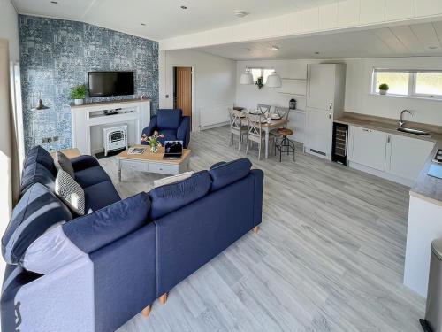 a living room with a blue couch and a kitchen at Hoburne in Bodmin