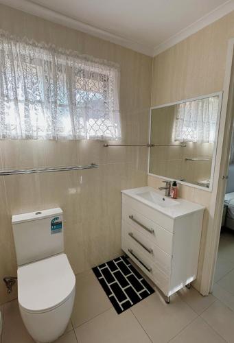 a bathroom with a toilet and a sink and a mirror at Ella sweet home in Algester