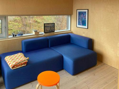 a blue couch in a room with a window at Beachfront Cabin Overlooking The Coast in Hosen