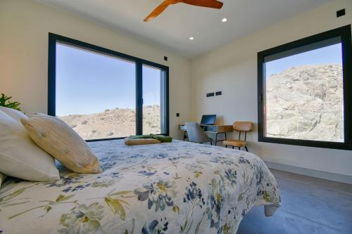 a bedroom with a bed and two large windows at La Atalaya del Salobre Golf in San Bartolomé