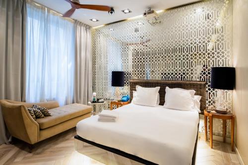 een slaapkamer met een bed, een stoel en een bank bij Abalú Collection Boutique Gran Via in Madrid
