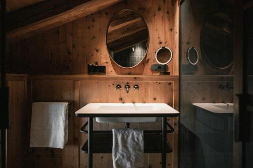 a bathroom with two sinks and two mirrors at Historic Alpine Lodge In The Heart Of South Tyrol in Villandro