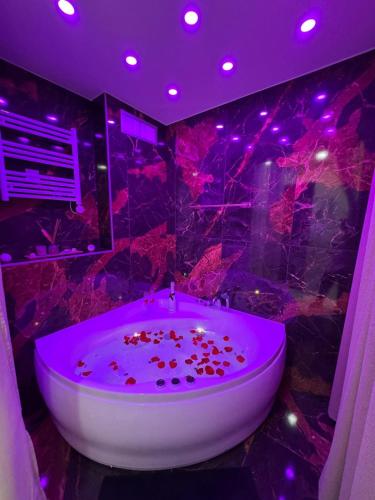 a bathroom with a large tub with purple lighting at L'Écrin Secret Romantic Love Room & Private Spa in Ambilly