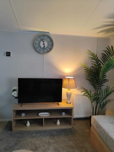 a living room with a tv and a clock on the wall at 3 Bedroom Static Caravan, Sleeps 8, New 2025! in Hartley