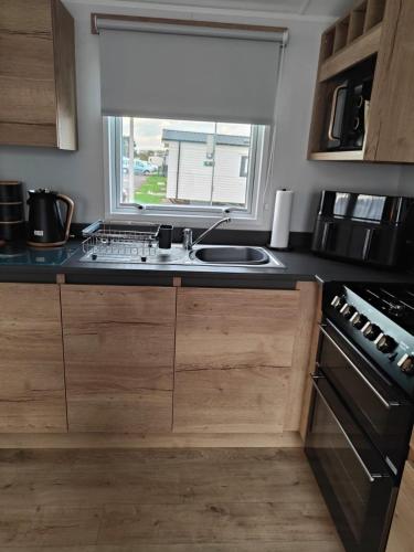 a kitchen with a sink and a window at 3 Bedroom Static Caravan, Sleeps 8, New 2025! in Hartley