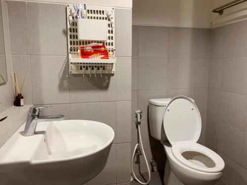 a bathroom with a white toilet and a sink at Cozy Studio Bintaro Icon Emerald by alonelyroom in Pondokaren