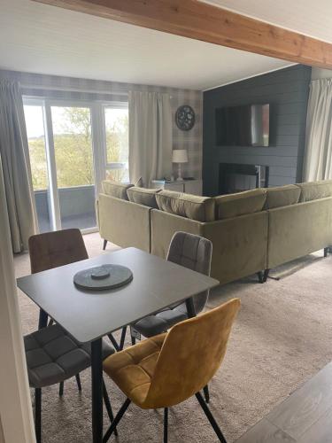 un soggiorno con tavolo, sedie e divano di Cosy north Devon lodge within Hartland forest a Exeter