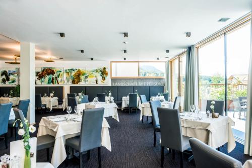 a restaurant with white tables and chairs and windows at Villa Waldkönigin in San Valentino alla Muta