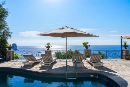 a pool with chairs and an umbrella and the ocean at Villa Danima in Capri