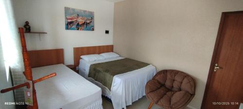 a small room with two beds and a chair at Pousada Santo Rio in Olho D’Água do Casado