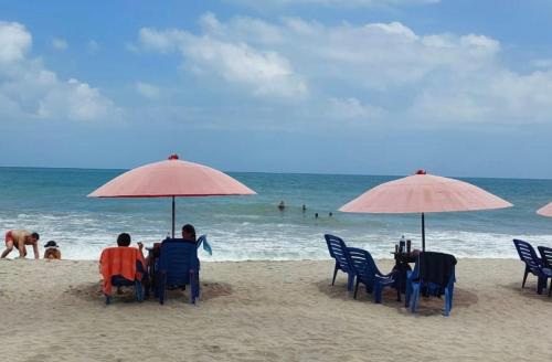a group of people sitting under umbrellas on a beach at Hostel casa jungla in Palomino