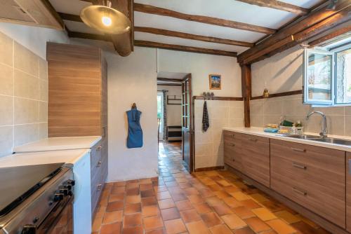 a large kitchen with wooden cabinets and a tile floor at Charmante Bergerie in Castet