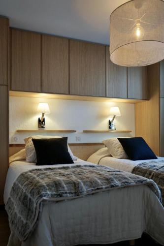 een slaapkamer met twee bedden en een hanglamp bij Muguets 4 in La Clusaz