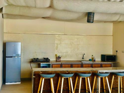 a kitchen with a counter with a refrigerator and stools at Desert Breeze Resort in Ras al Khaimah