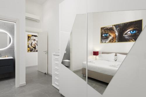 a white bedroom with a blue eye painting on the wall at Borghese Palace Luxury Apartment in Florence