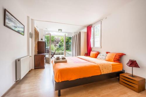 a bedroom with a bed with orange sheets and a window at Les Marguerites - Pavillon, Wifi, TV, 2 Parkings in Chevilly-Larue