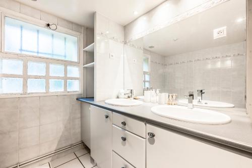 a white bathroom with two sinks and a window at Les Marguerites - Pavillon, Wifi, TV, 2 Parkings in Chevilly-Larue