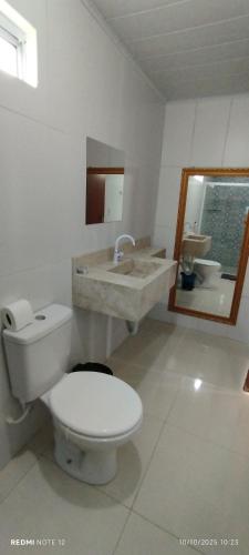 a white bathroom with a toilet and a sink at Pousada Santo Rio in Olho D’Água do Casado