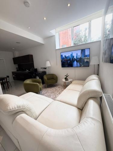 a living room with a white couch and a tv at Kings Cross St Pancras One Bedroom Flat in London